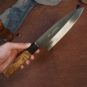 The Japanese Deba knife being held showcasing the gorgeous Burl wood handle  